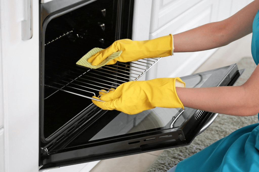 Gloved hands wiping down an oven rack during a deep clean